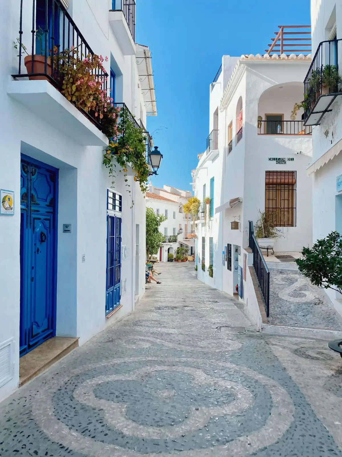 Calle de casas blancas y puertas azules en el casco antiguo de Frigiliana.