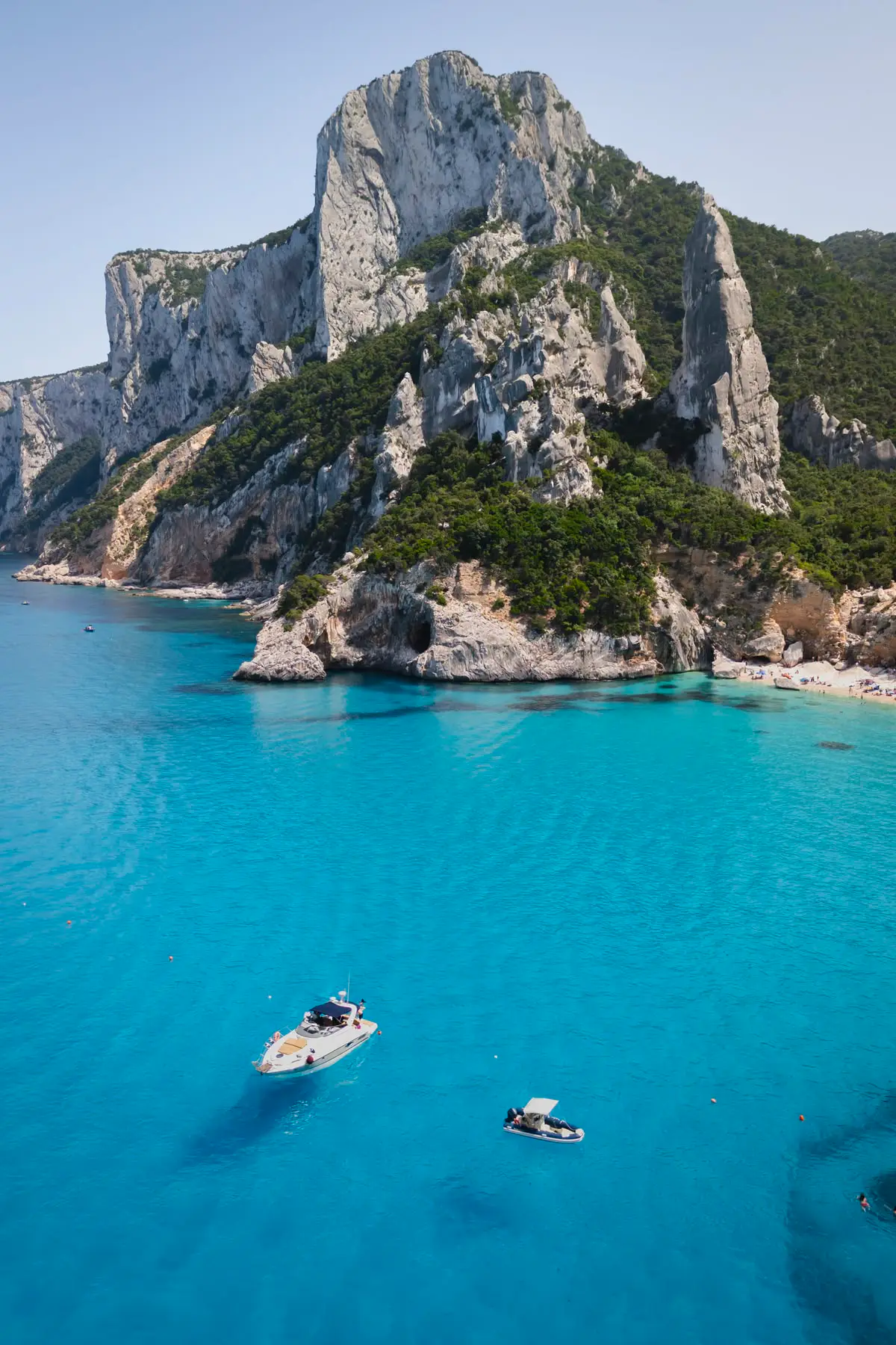 Acantilados calizos y aguja de roca junto a las aguas turquesas de Cala Goloritzé, Baunei, Cerdeña.