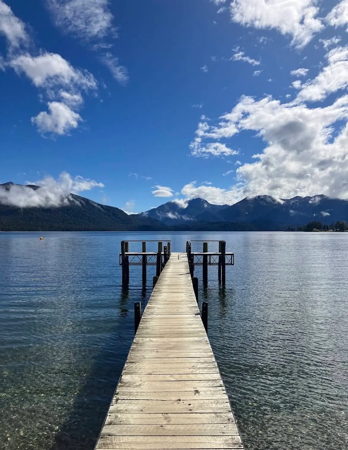 Lago Te Anau, Nueva Zelanda, con un embarcadero y montañas al fondo.