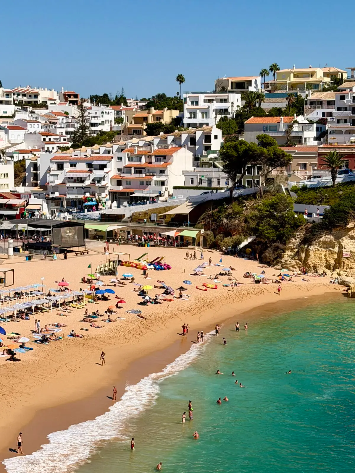 Casas blancas junto a la playa de Carvoeiro, con arena y aguas turquesas del Algarve.