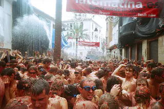 Multitud cubierta de tomate en las calles de Buñol durante La Tomatina