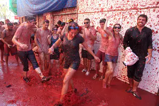Grupo de participantes entre calles teñidas de rojo por La Tomatina